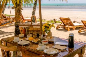 Pousada Enero في ماراغوغي: طاولة خشبية على الشاطئ عليها طعام