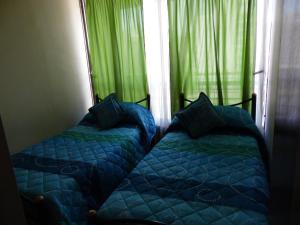 two beds in a room with green curtains at Kuizi departamento Manuel Montt in Santiago