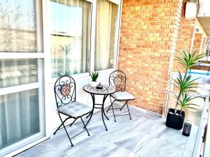 patio z 2 krzesłami i stołem na balkonie w obiekcie Downtown Dream Apartmans w Segedynie