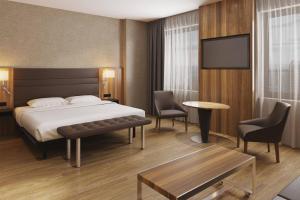 AC Hotel by Marriott Riga في ريغا: غرفة فندق بسرير وتلفزيون