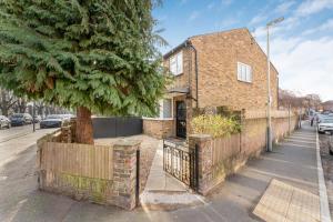 a brick house with a tree and a fence at Comfort Zone in Yiewsley