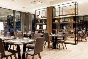 un restaurante con mesas y sillas de madera y paredes de cristal en AC Hotel by Marriott Riga en Riga