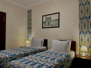 a hotel room with two beds and a picture on the wall at Hotel Saidkasim with a Terrace in Bukhara
