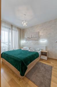 NEO Apartman في زلاتيبور: غرفة نوم بسرير وبطانية خضراء