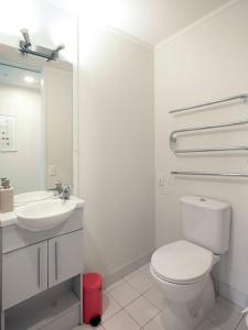 a white bathroom with a toilet and a sink at Cozy apartment in Grafton in Auckland