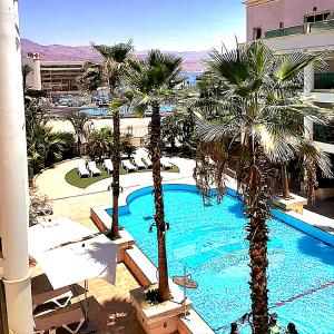 a resort with palm trees and a swimming pool at Milana's Deluxe with big patio and pool in Eilat