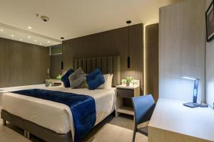 1 dormitorio con cama, escritorio y silla en 4 Sur Hotel en Medellín