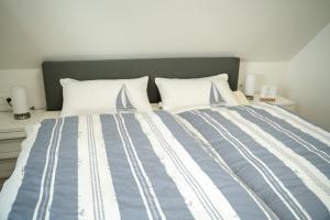a bed with blue and white sheets and pillows at Urlaub an der Nordsee - NEU - Ferienhaus Deichliebe in Fedderwarderdeich