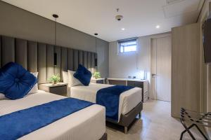 a hotel room with two beds with blue pillows at 4 Sur Hotel in Medellín +68 photos