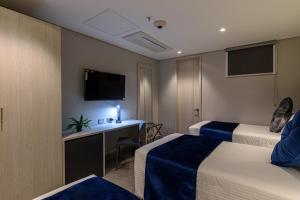 um quarto de hotel com duas camas e uma secretária em 4 Sur Hotel em Medellín