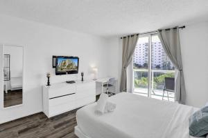 een witte kamer met een bed, een tv en een raam bij Ocean reserve On the Beach Best Location in Miami Beach