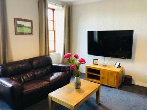 a living room with a leather couch and a television at Bonnygate in Fife