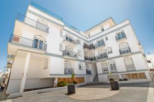 a large white building with potted plants in front of it at City apartment with workspace, rooftop & parking in Tarifa +8 photos