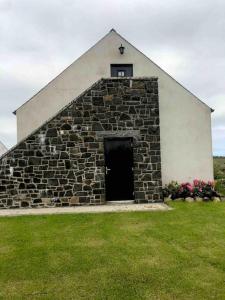 a stone building with a door in a field of grass at Lily’s Loft Bushmills in Bushmills