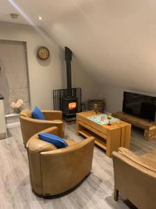 a living room with chairs and a fireplace and a tv at Lily’s Loft Bushmills in Bushmills