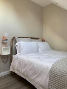 a bedroom with a bed with white sheets and a lamp at Lily’s Loft Bushmills in Bushmills