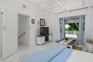 a white bedroom with a bed and a tv at Golf Beach and Sea in Southbroom
