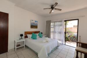 a bedroom with a bed with blue pillows and a window at Nothando Backpackers Lodge in Plettenberg Bay