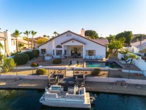 a house with a boat in the water at Waterside - Lavish Lakeside Property with Heated Pool and Pontoon Boat in Peoria