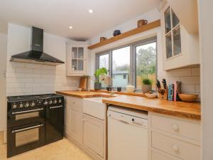 a kitchen with white cabinets and a black stove top oven at Little Foxes in Calne