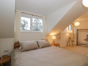 a bedroom with a white bed with a window at Little Foxes in Calne
