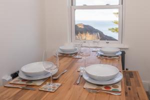 a dining table with plates and glasses and a window at Larkrise Penthouse Apartment in Woolacombe