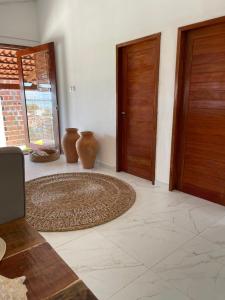 Cette chambre dispose de deux portes en bois et d'un tapis. dans l'établissement Casa Refúgio, à Galinhos