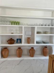 a white shelf with vases and plates on it at Casa Refúgio in Galinhos
