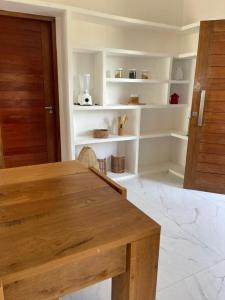 a dining room with a wooden table and white shelves at Casa Refúgio in Galinhos