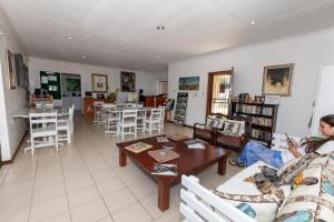 a woman sitting on a couch in a living room at Nothando Backpackers Lodge in Plettenberg Bay