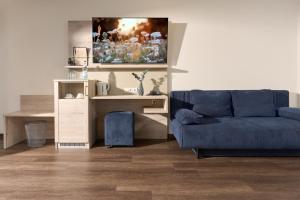 فندق أبولون روست في روست: غرفة معيشة مع أريكة زرقاء ومكتب