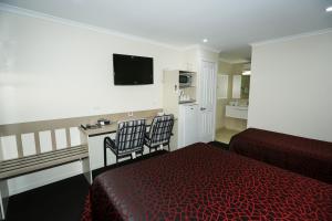 a hotel room with two beds and a television at Amber Lodge Motel in Gladstone