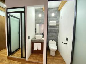 two pictures of a bathroom with a toilet and a mirror at Suites del Barrio in San Cristóbal de Las Casas