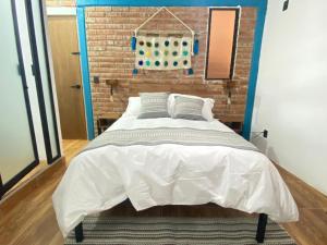 een bed in een kamer met een bakstenen muur bij Suites del Barrio in San Cristóbal de Las Casas