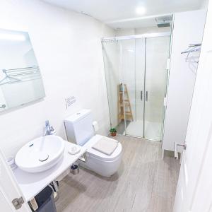 a bathroom with a toilet and a sink and a shower at City apartment with workspace, rooftop & parking in Tarifa
