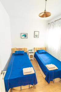 a bedroom with two beds with blue sheets at City apartment with workspace, rooftop & parking in Tarifa