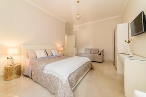 a white bedroom with a large bed and a couch at HomeAway Salerno in Salerno