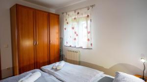 Schlafzimmer mit einem Bett mit weißer Bettwäsche und einem Fenster in der Unterkunft Apartma Tri oljke in Dobrovo