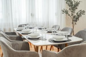 a table with chairs and a white table set with plates and glasses at LUXURY-Apartment - city center : 8 guests : Netflix in Saarbrücken