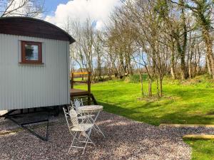 a shed with two chairs and a table next to it at Lilliput - Delightful 1-bedroom shepherd's hut in Holsworthy