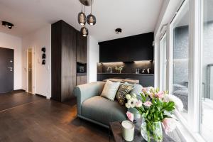 una sala de estar con sofá y un jarrón de flores en Apartamenty Tespis - Sokolska 30 Towers en Katowice