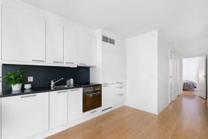 a white kitchen with white cabinets and a wooden floor at Tjuvholmen - ved Aker Brygge in Oslo