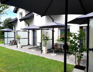 a group of tables with umbrellas in front of a building at Apartamenty Sol Mare in Sarbinowo