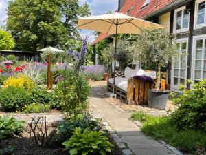 a garden with a bench and an umbrella at Xanadi Heilehaus kleine Auszeit Kururlaub in Bruchhausen-Vilsen