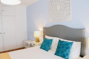 a bedroom with a white bed with blue pillows at Amélia - Always Algarve in Armação de Pêra