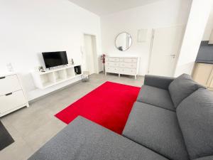 - un salon avec un canapé et un tapis rouge dans l'établissement Wohnung in Kassel mit Ladesäulen, à Cassel