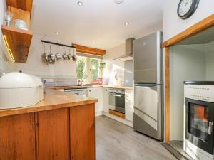 una cocina con armarios de madera y electrodomésticos de acero inoxidable en Woodfield Coach House, en Merrymeet