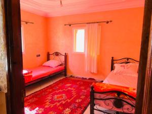 a room with two beds and a red rug at appartement Ocean in Tamraght Ouzdar