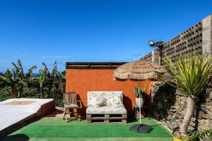 un patio con una silla y una sombrilla de paja en Cute Villa with Views and Pool, en Santa María de Guía de Gran Canaria
