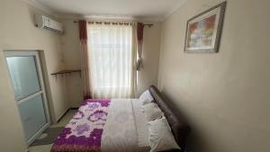 um quarto com uma cama com um edredão roxo e uma janela em Lao Tangren Guest House em Kigali